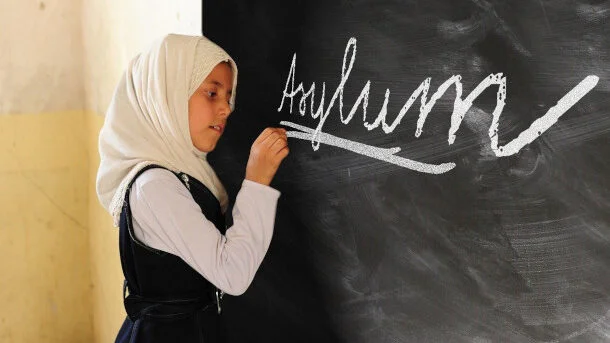 Fetiță scriind "azil" pe tablă