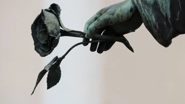 Statuie reprezentând o mână de înger ținând un trandafir